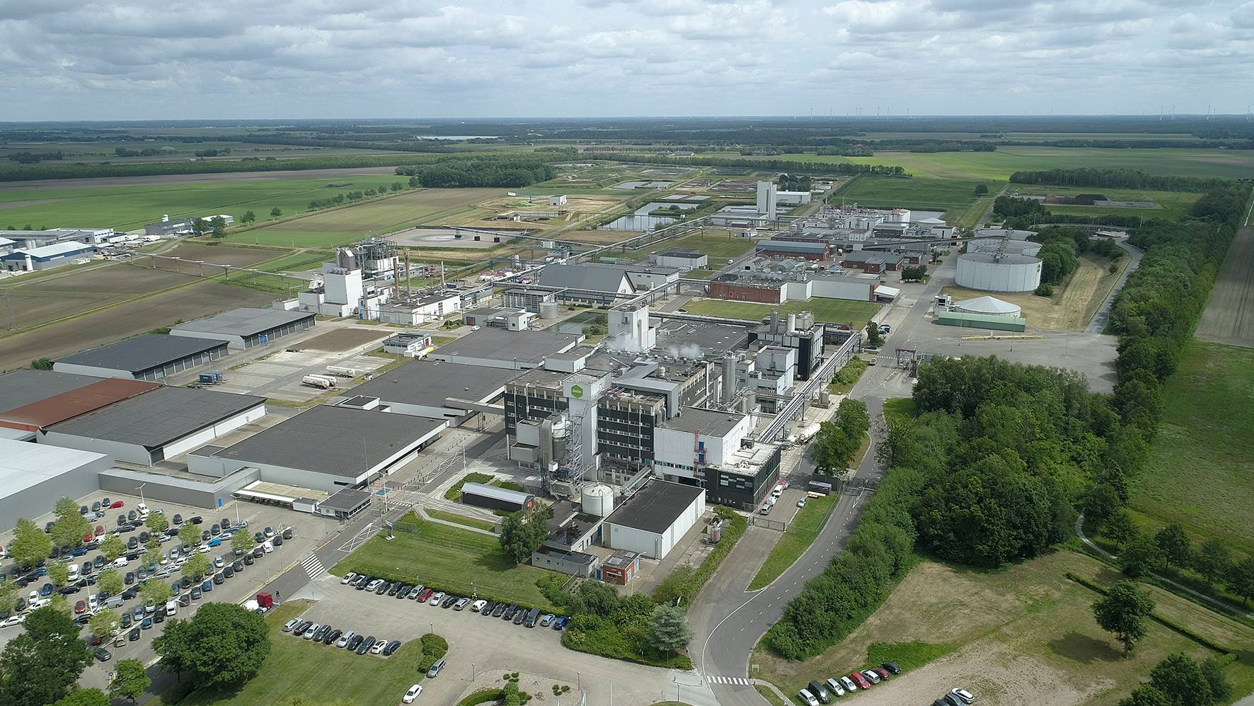 Aerial view of a factory with green surroundings